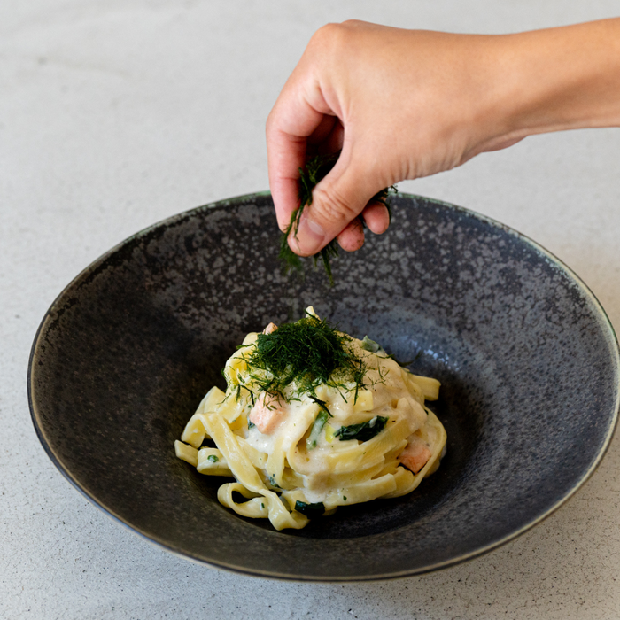 A bowl of carbonara pasta topped with dried aonori