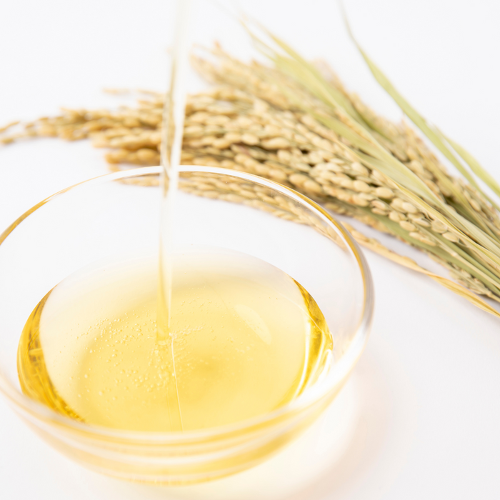 A bowl of Pure Rice Bran Oil next to a bunch of rice