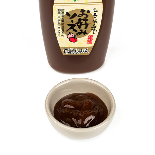 A bowl of okonomiyaki sauce in front of the package bottle of the product