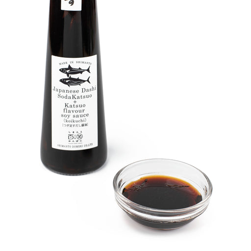 A bowl of soy sauce next to a bottle of the product