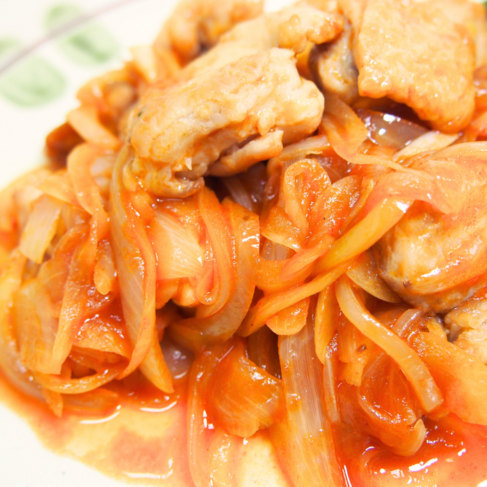 A plate of grilled chicken and onion with tomato ketchup sauce