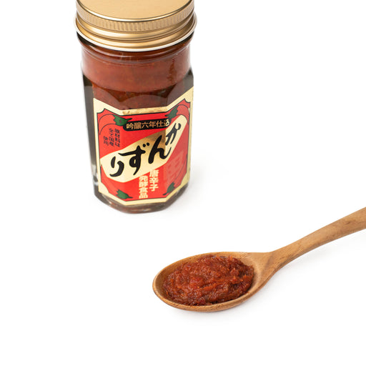 A spoon of kanzuri chili sauce next to a package jar of the product