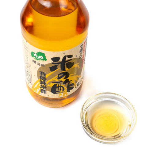 A small bowl of organic rice vinegar with bottle of the product