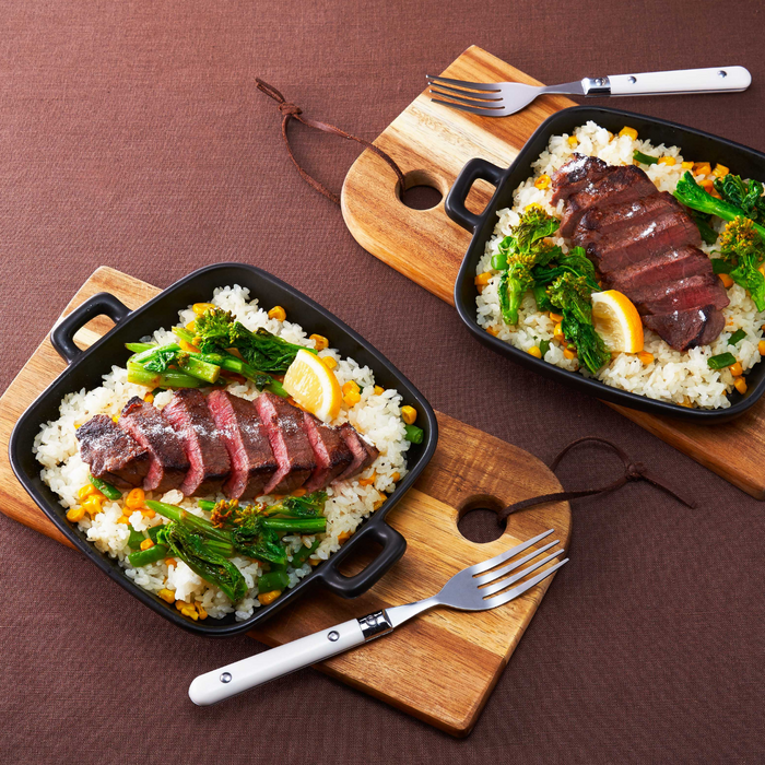 Two plates of pilaf topped with beef steak.