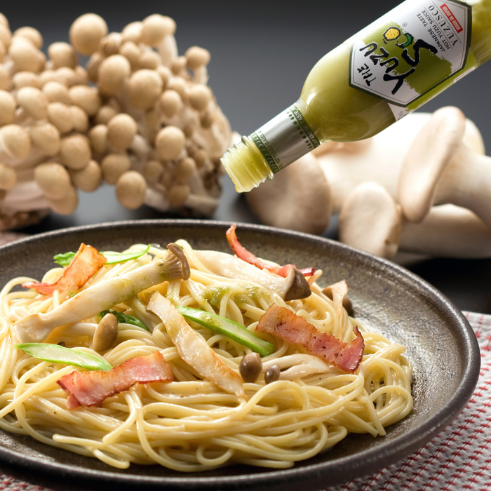 Man pouring yuzu hot sauce onto pasta dish