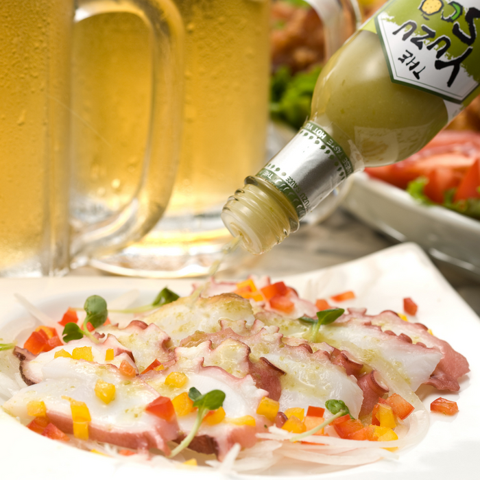 Man pouring yuzu hot sauce onto octopus carpaccio