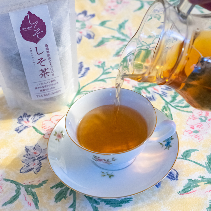 Man pouring shiso tea into cup from glass tea pot