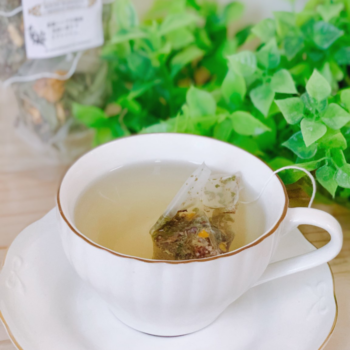 A cup of Ehime Mikan Tea in front of green leaves