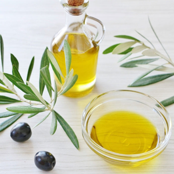A bowl of the yuzu extra virgin olive oil next to olives