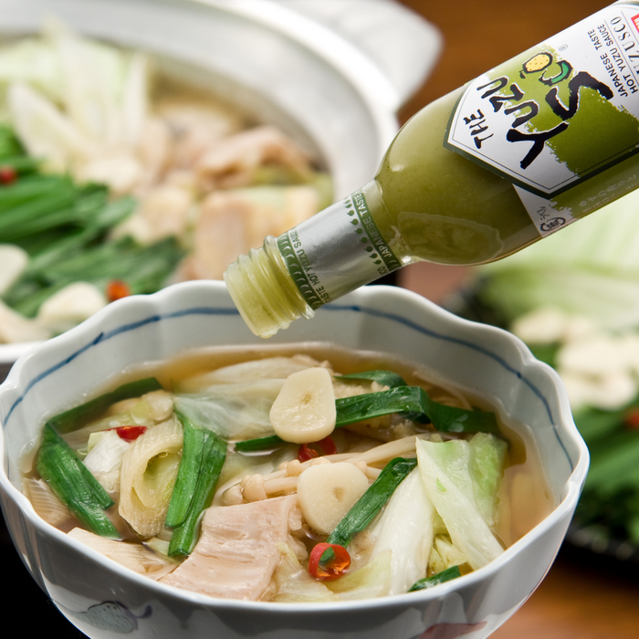 Man pouring yuzu hot sauce onto a bowl of soup