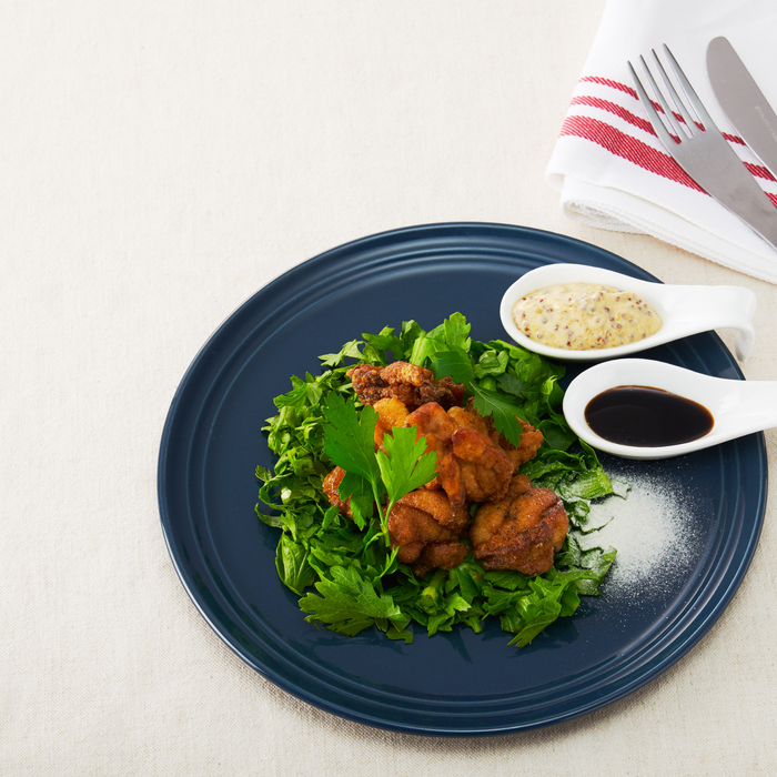 A plate of fried chickens with spoons of soy sauce and mustard