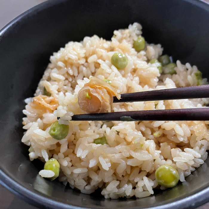 Man taking a piece of clam from seasoned rice with chopsticks