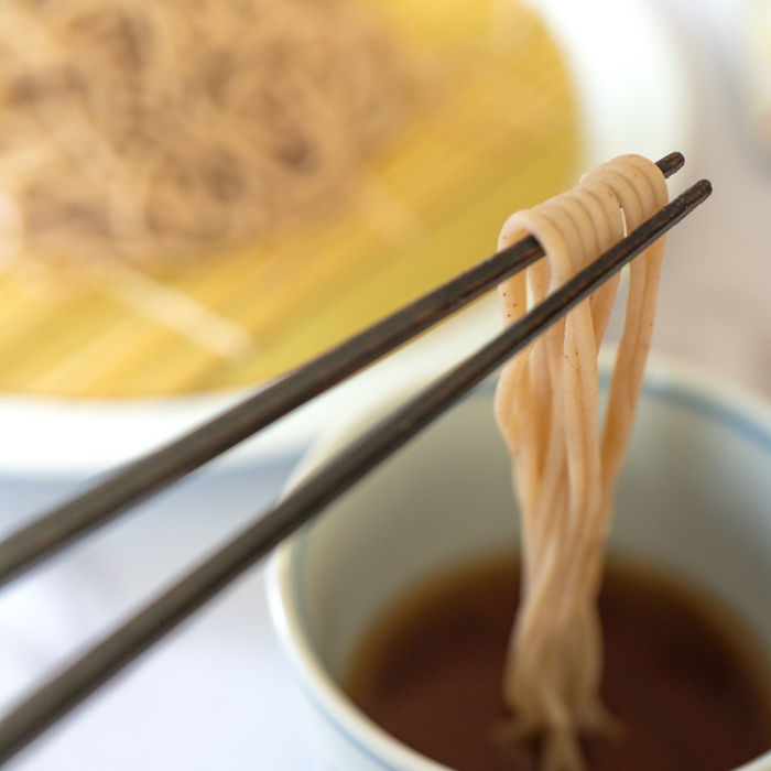 Man taking cold juwari soba noodles with chopsticks