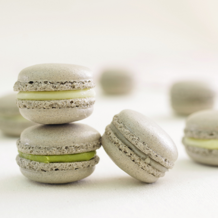 A couple of black sesame macarons stuffed with matcha cream