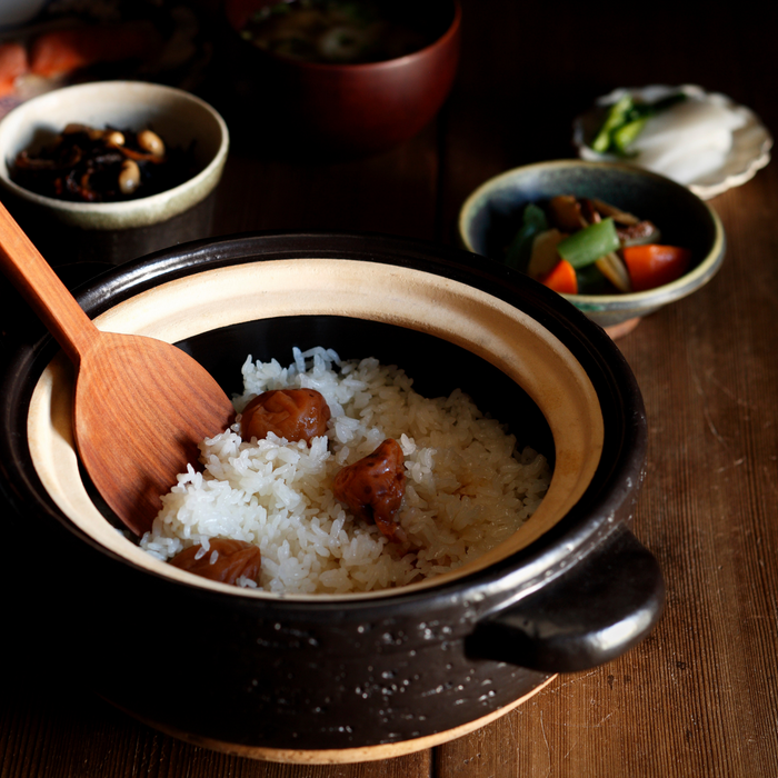 A ceramic pot filled with steamed white rice with three pieces organic umeboshi