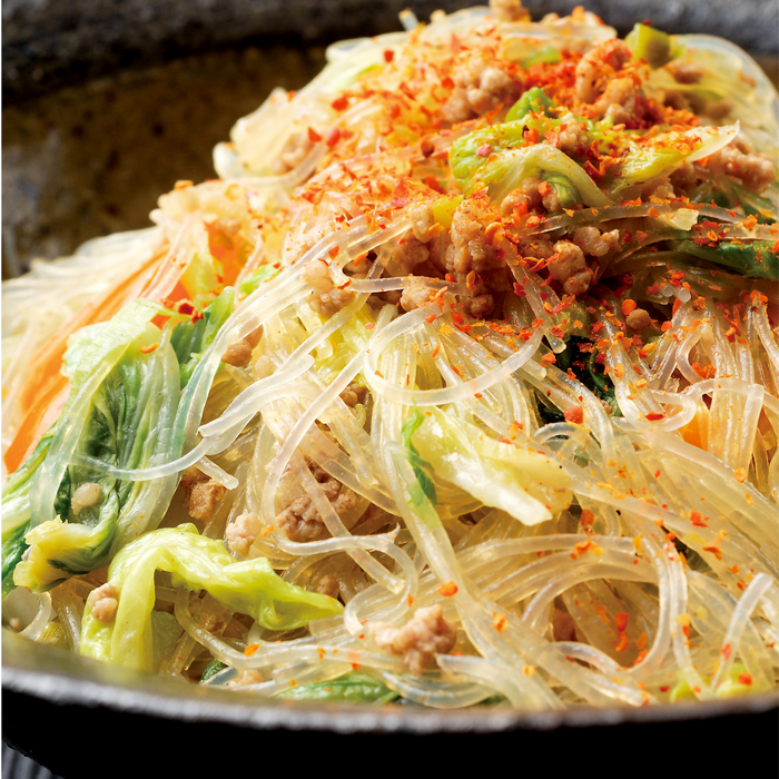 A plate of stir-fried clear rice noodles tipped with ichimi pepper