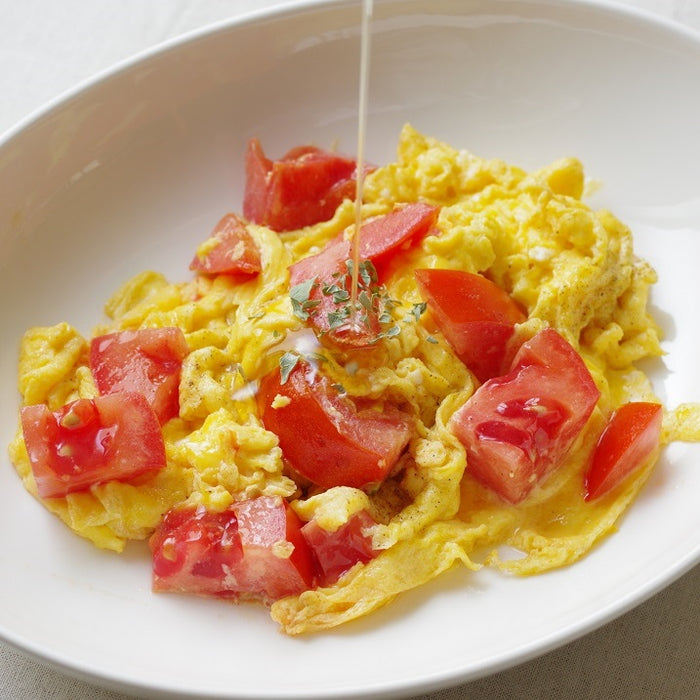 A plate of omelette being drizzled with sesame oil