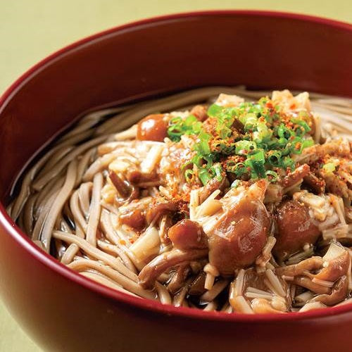 A bowl of soba noodles topped with shichimi togarashi pepper powder and mushrooms
