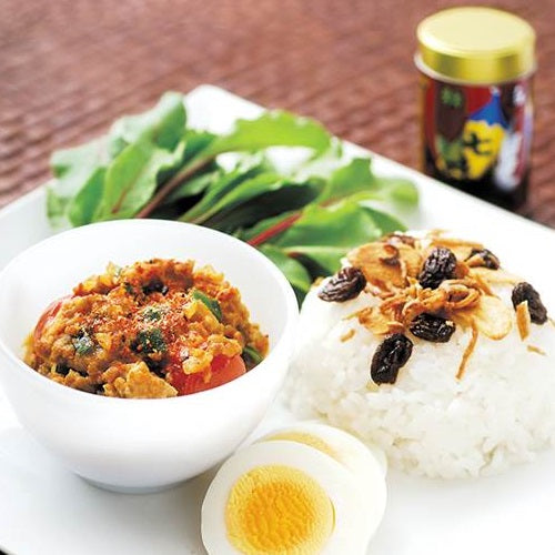 A bowl of stir-fried ground pork topped with shichimi togarashi pepper powder next to steamed rice and boiled egg