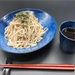 A bowl of cold soba noodles and dipping sauce on the side