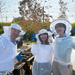 Three beekeepers surrounded by lots of flying bees