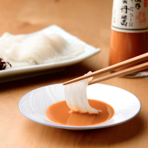 Dipping sliced squid into uni sauce