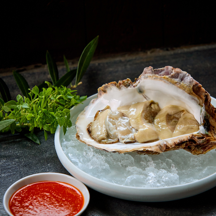A raw oyster and a bowl of motoi sauce