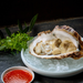 A raw oyster and a bowl of motoi sauce