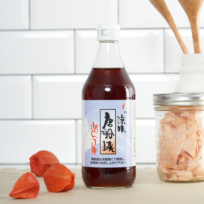 A package bottle of mentsuytu next to a jar of bonito flakes