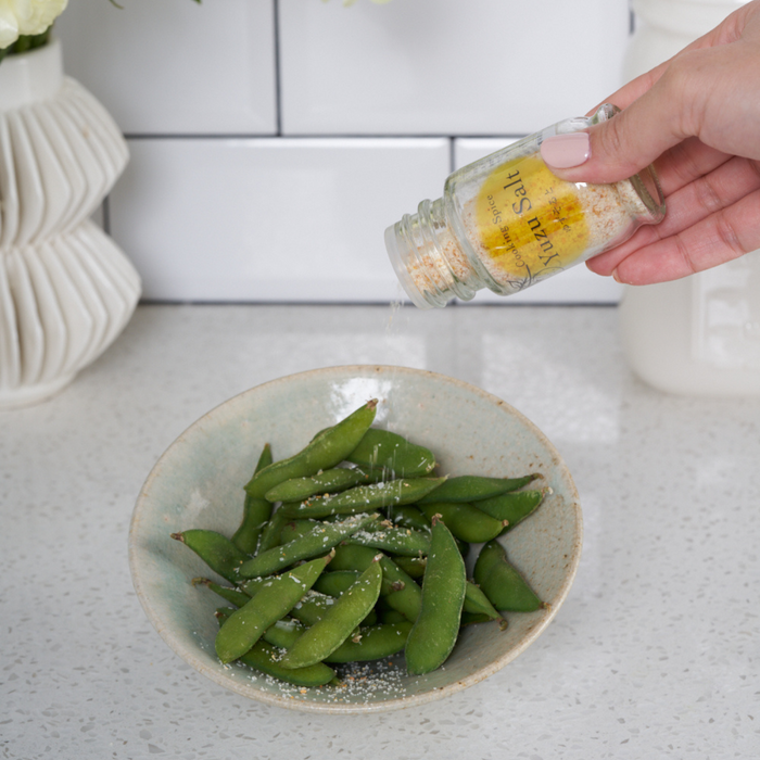 Man sprinkling yuzu salt onto edamame