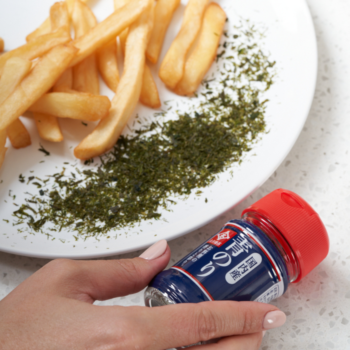 A bottle of dry aonori seaweed next to french fries