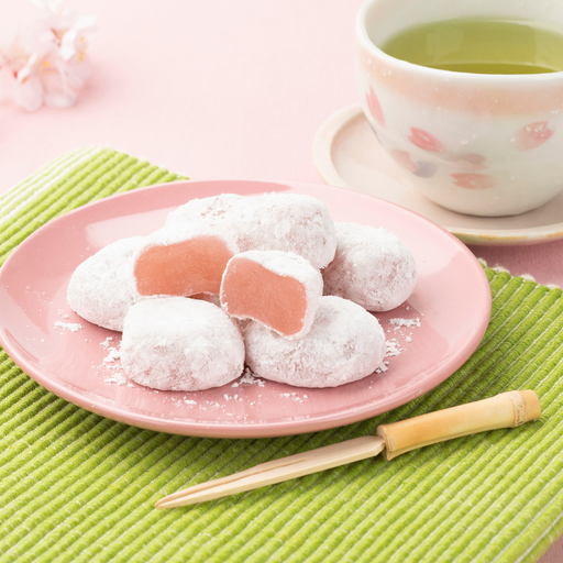 A plate of mochi being cut next to matcha bowl