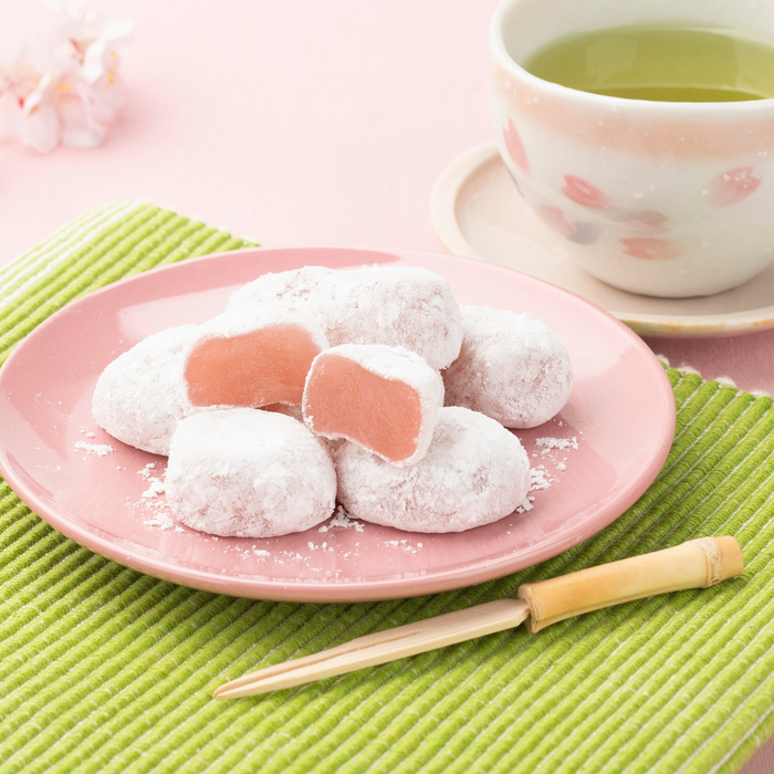 A plate of mochi being cut next to matcha bowl