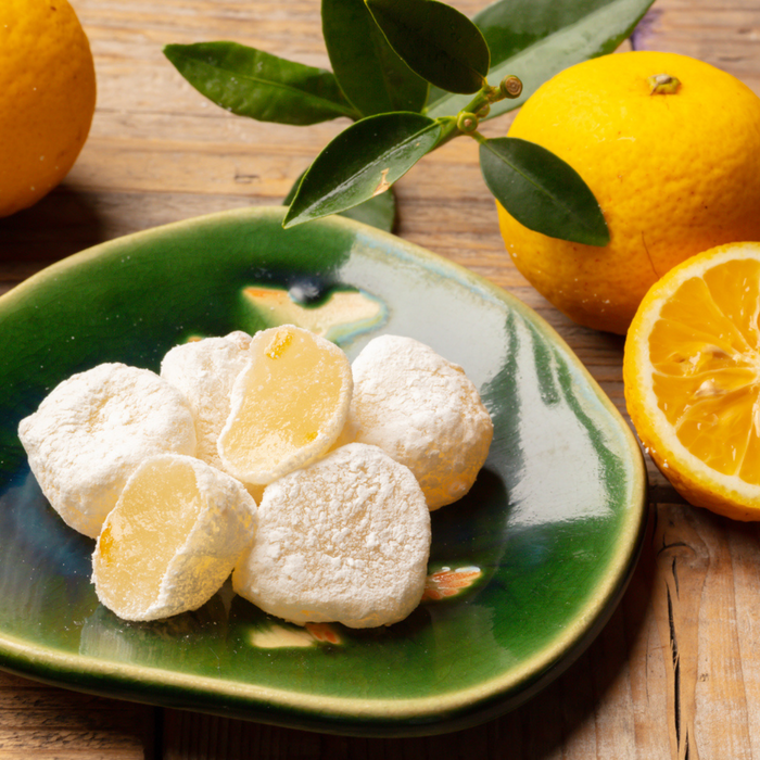 A plate of yuzu mochi next to yuzu citruses