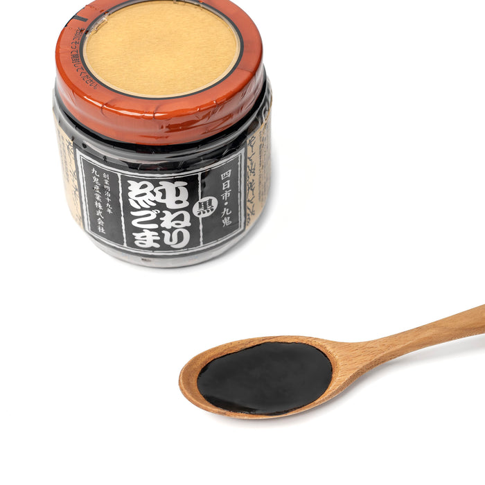 A spoon of black sesame paste next to bottle of the product
