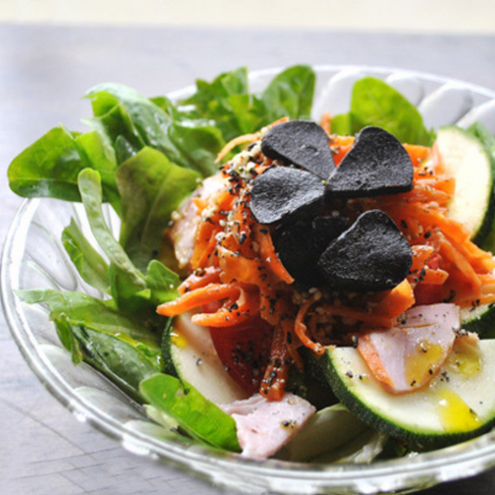 A salad bowl topped with sliced black garlic