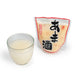 A glass of amazake next to package of the product