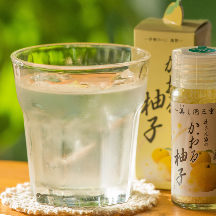 A glass of yuzu soda next to a package bottle of the product
