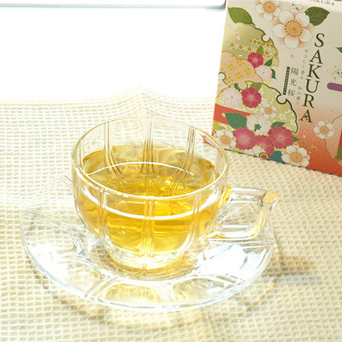A cup of sakura leaf tea next to a package of the product