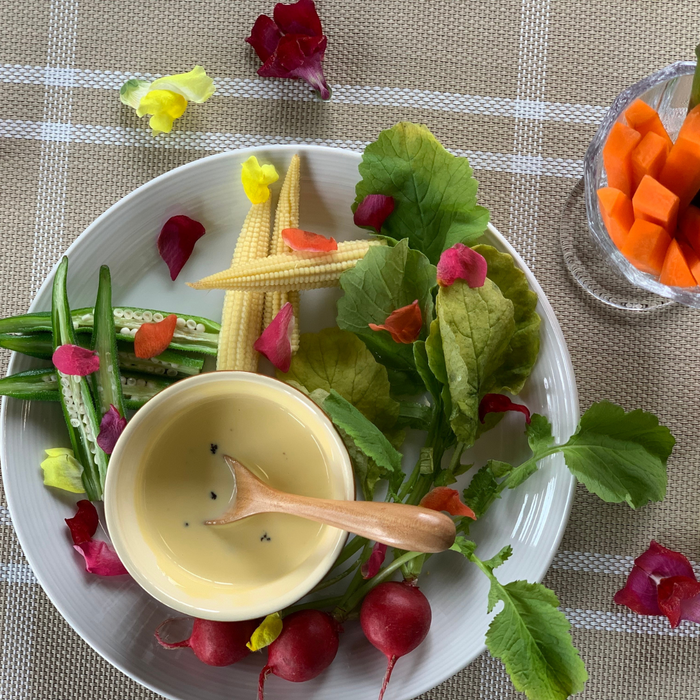 A salad plate with a bowl of dipping sauce