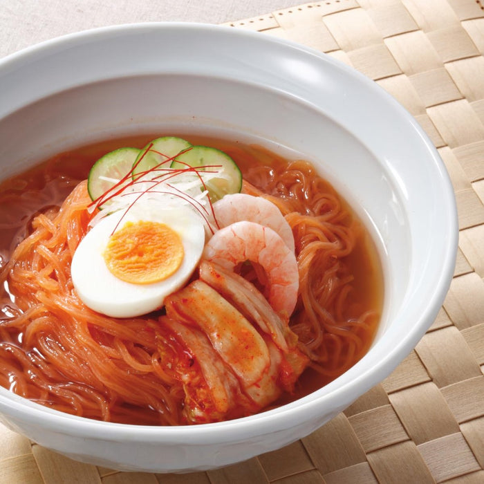 A bowl of carrot blended shirataki noodles soup topped with boiled eggs and shrimps