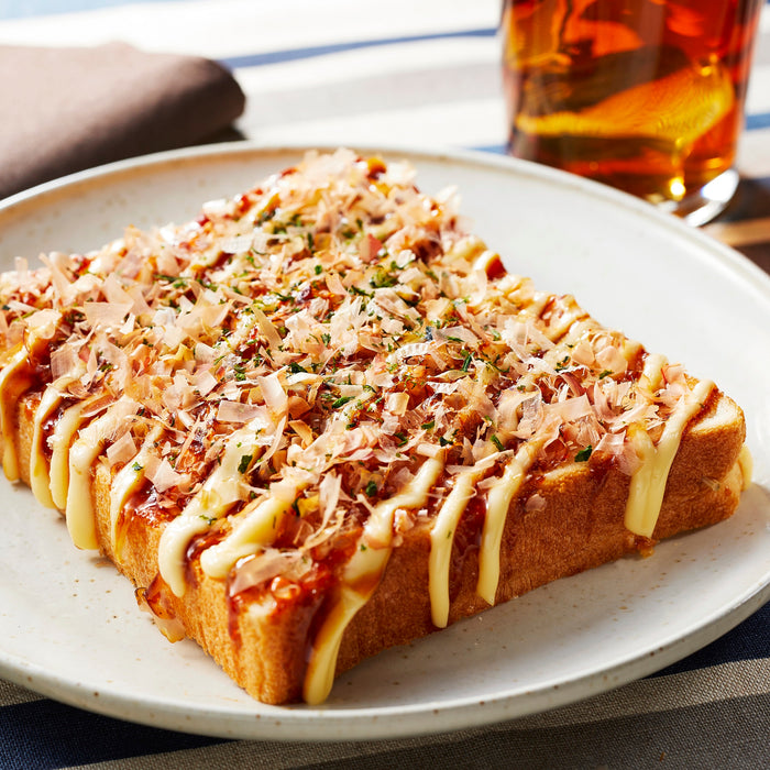 A slice of toast topped with dried bonito flakes, mayo and brown sauce
