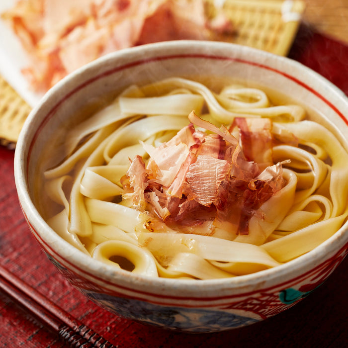 A bowl of hot udon noodles soup topped with dried bonito flakes